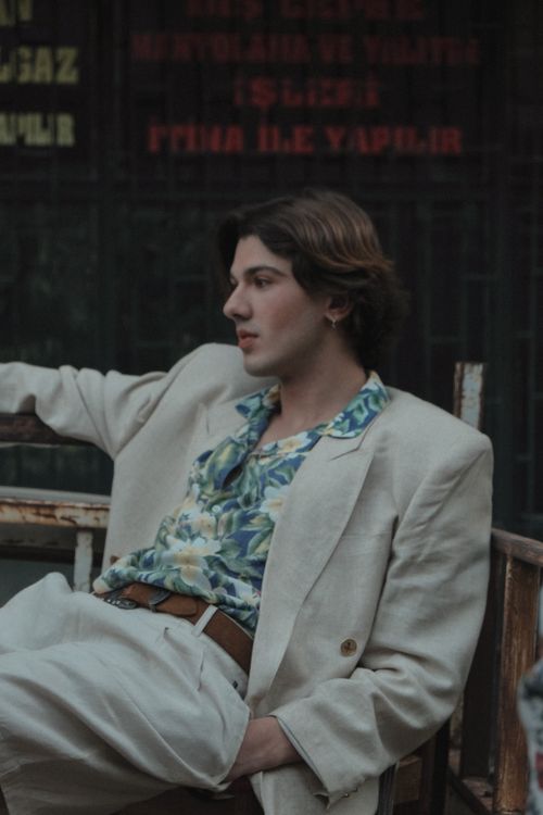 Free Fashionable young man in a beige suit sitting in an urban environment, exuding a relaxed vibe. Stock Photo