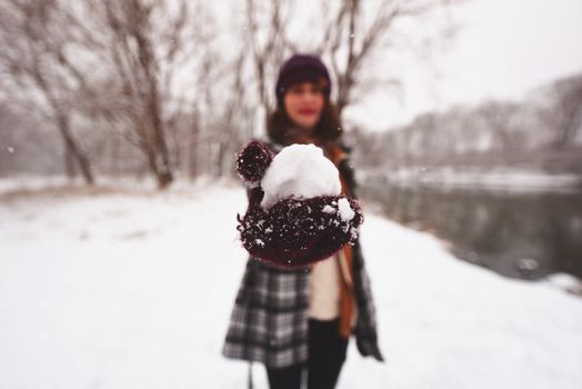 一个年轻女人在白雪皑皑的冬日景色中拿着雪球