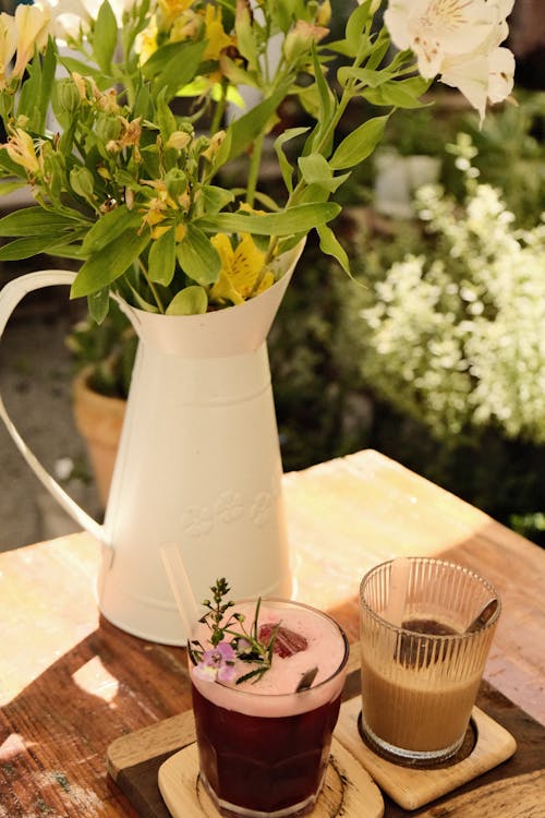 Two Glasses with Drinks and Flowers in a Vase