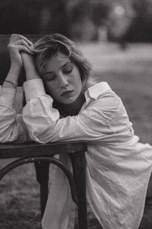Free Elegant black and white portrait of a woman resting on a chair with eyes closed. Stock Photo