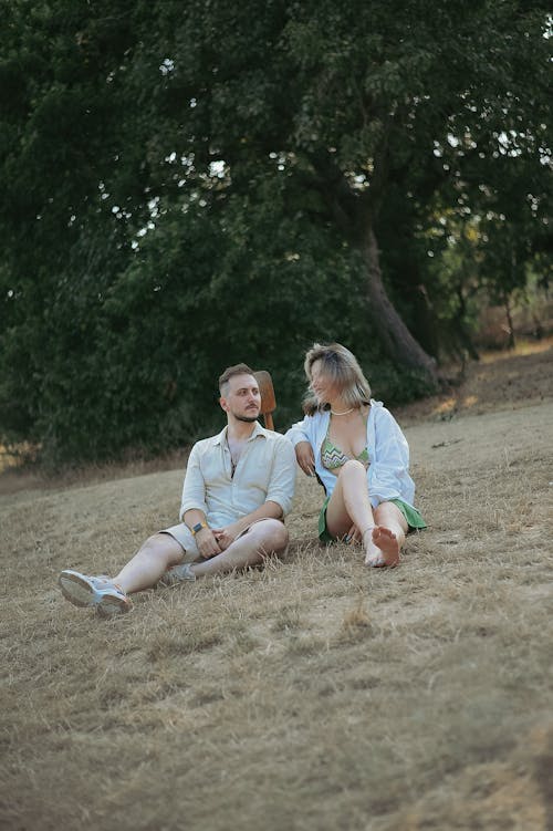 Couple in Shirts Sitting on Grassland