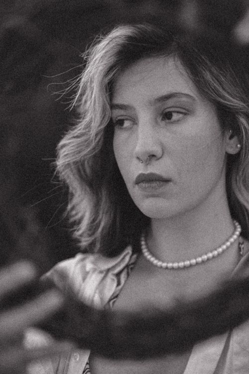 Free Black and white portrait of a young woman with long hair and necklace, looking contemplative. Stock Photo