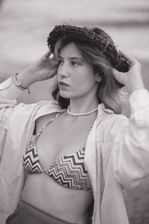 Free Chic black and white portrait of a young woman wearing a wicker hat on the beach. Stock Photo