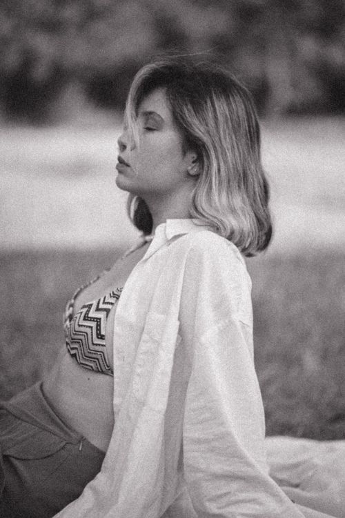 Free A calming monochrome portrait of a woman sitting outdoors with eyes closed, embracing a summer vibe. Stock Photo