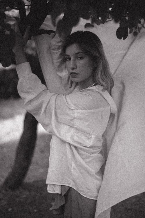 Free Moody black and white portrait of a young woman in a stylish pose outdoors. Stock Photo