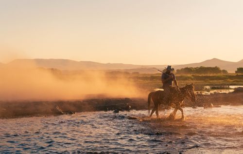Free A cowboy riding a horse through water at sunset in Hürmetci, Kayseri, Turkey. Stock Photo
