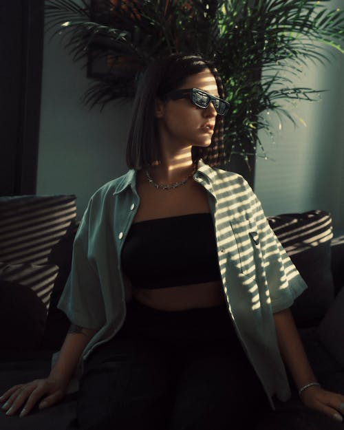 Young Woman Posing in a Shadow in a Room with Sunglasses on
