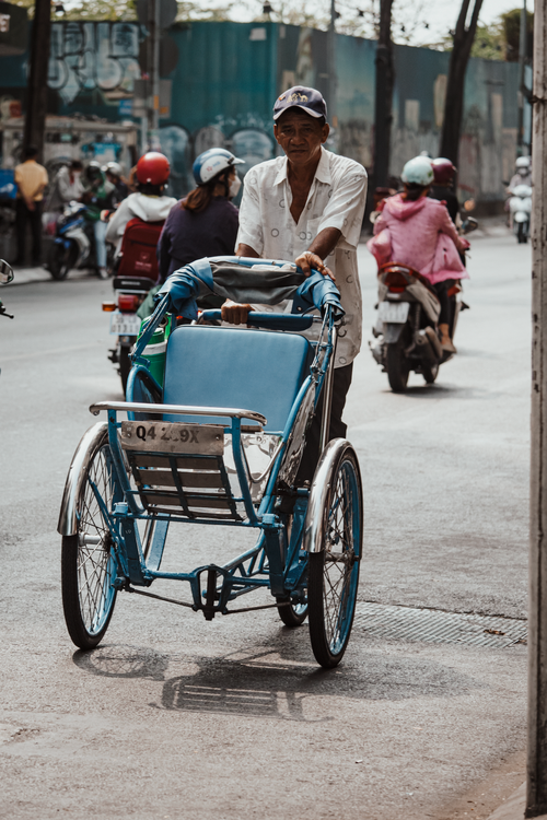 Free A man pushes a cyclo through the bustling streets of Ho Chi Minh City, Vietnam. Stock Photo
