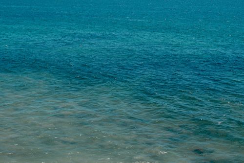 Free A serene view of the ocean with gentle waves under a clear blue sky, perfect for relaxation themes. Stock Photo