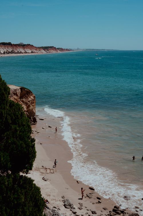Free Sunny seaside view with people relaxing along the sandy coastline. Stock Photo