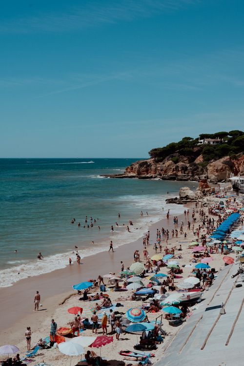 Free Crowded beach scene with sunbathers and swimmers under a clear sky. Stock Photo
