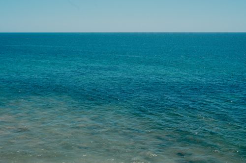 Free Peaceful ocean scene with a clear horizon and gentle waves under a blue sky. Stock Photo
