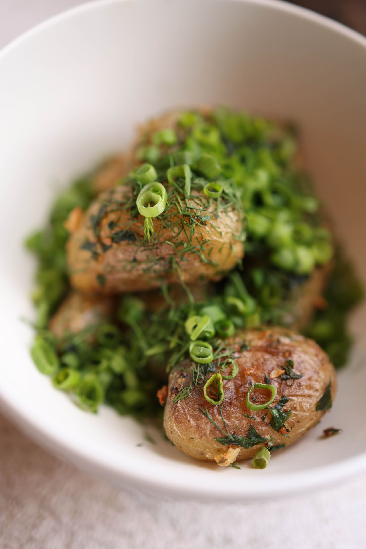 Roasted potatoes with fresh herbs in a white bowl