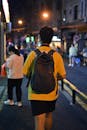 Man Walking with Backpack on Street at Night