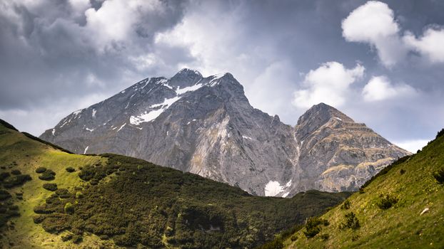 A breathtaking view of a dramatic alpine mountain peak under a cloudy sky.