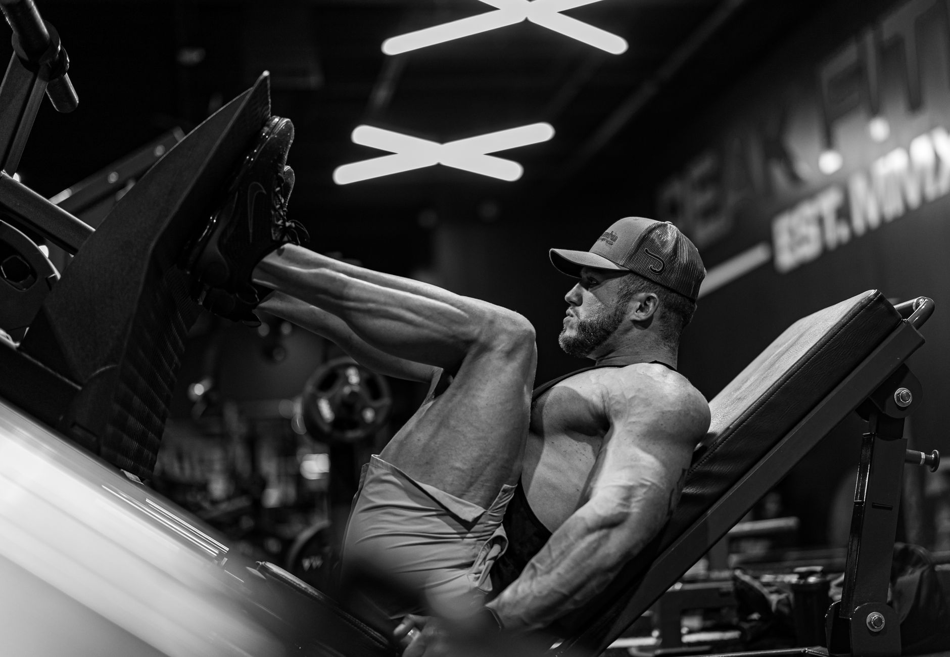 Strong muscular man performing leg press exercise in a modern gym setting.