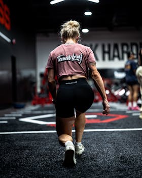 Fit woman kneeling during workout session at gym, highlighting strength and fitness.