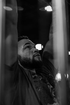 A black and white portrait of a man with a beard exercising indoors.