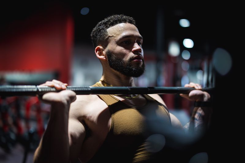 A Black man lifting a barbell at a gym, the audience peptide sellers market to most heavily.