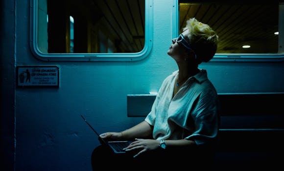 Stylish woman with laptop on nighttime train in Istanbul, Türkiye.
