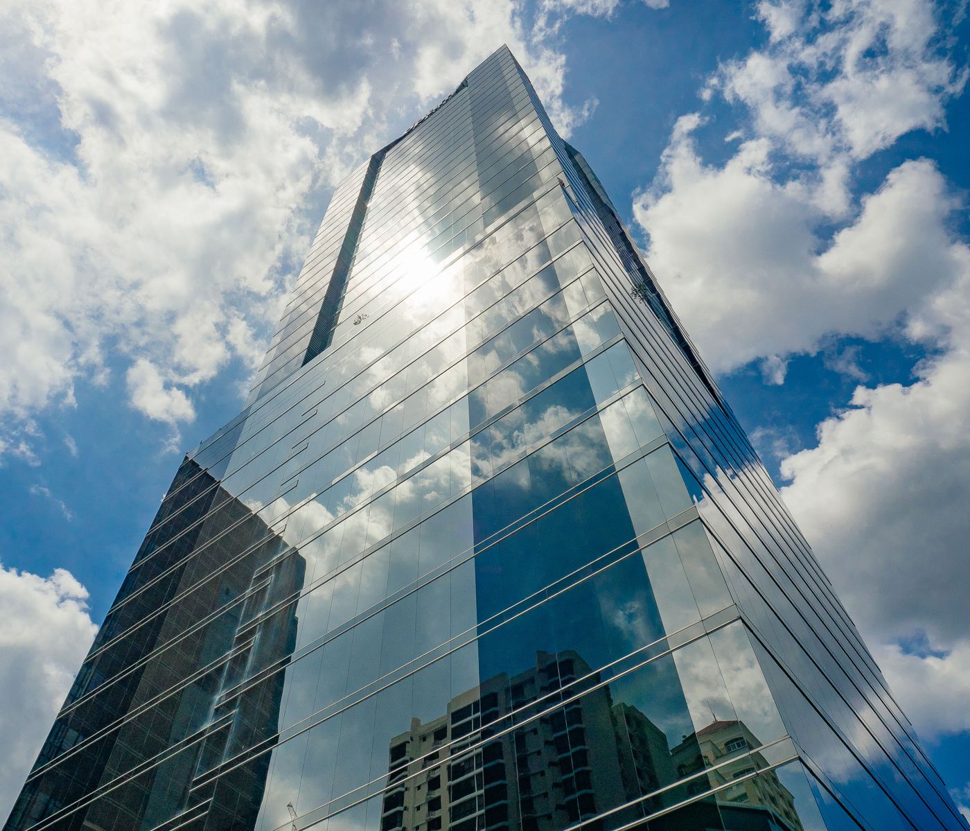 Modern glass office tower against a blue sky