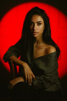 Striking portrait of a young woman posing gracefully against a bold red background.