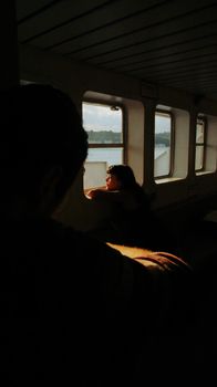 A woman gazes out a train window, bathed in warm sunlight, evoking a sense of introspection.