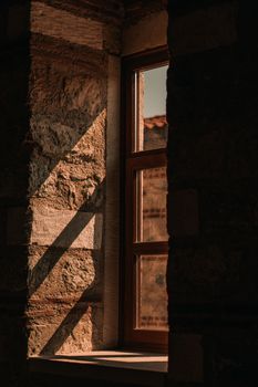 A rustic stone wall illuminated by sunlight casting dramatic shadows through a window frame.
