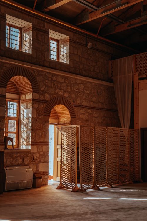 Free Sunlit interior of a historic building with stone arches and lattice partitions adds a moody atmosphere. Stock Photo