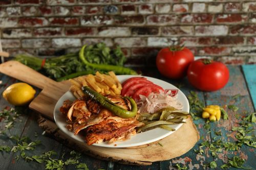 Free Delicious grilled chicken served with fries, tomatoes, and vegetables on a wooden cutting board. Stock Photo