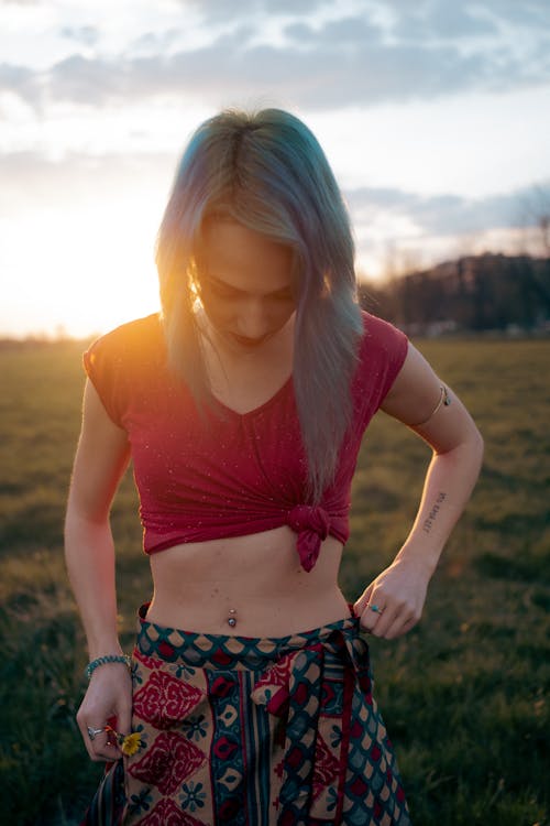 Young Woman Standing on a Meadow at Sunset 