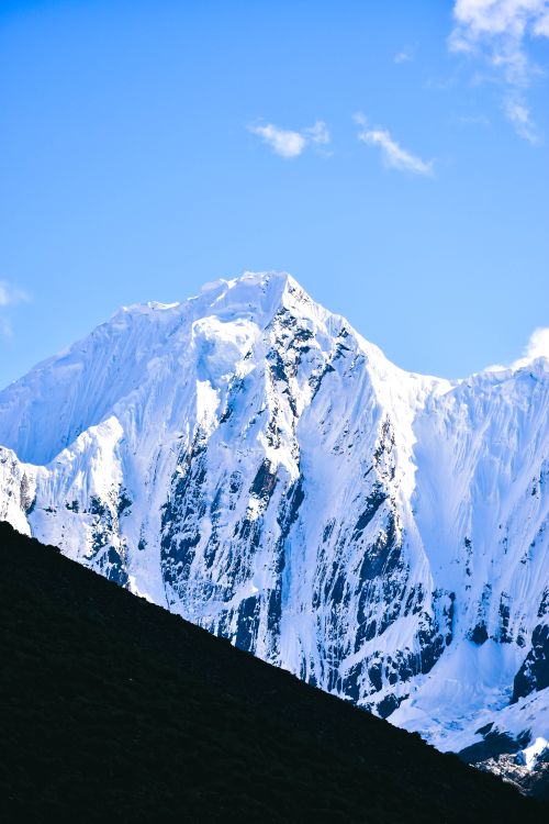 Free Stunning snow-covered mountain peak with a vibrant blue sky as the backdrop. Stock Photo