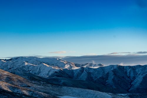 Free Stunning view of snow-capped mountains under a clear blue sky at sunrise. Stock Photo