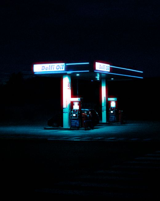 A brightly lit gas station stands solitary in the dark of night, showcasing its vibrant signage.