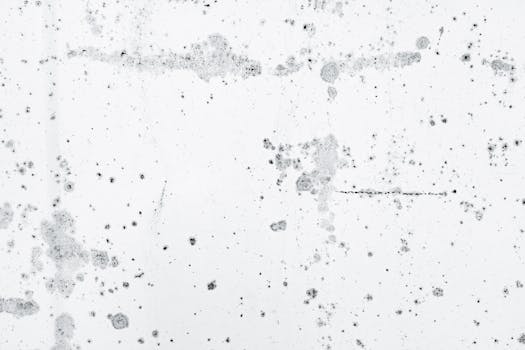 Detailed white concrete texture with black stains and spots, ideal for backgrounds.