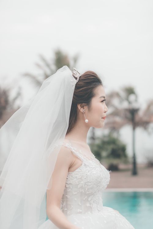 Free Beautiful bride in wedding gown by an outdoor poolside, capturing elegance. Stock Photo