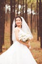 在宁静的森林中，美丽的新娘穿着白色礼服，手持一束鲜花