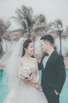 Outdoor wedding shoot featuring a smiling couple by the pool, capturing elegance and romance.