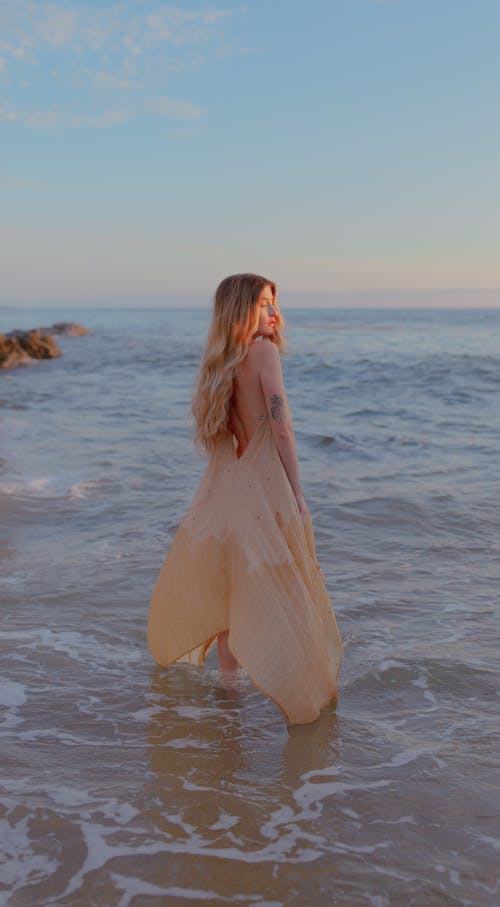 Young Woman in a Long Dress Standing Ankles Deep in the Sea 