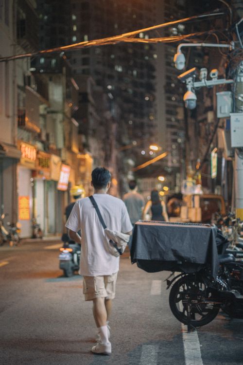 Free Back view of a man walking through a bustling city street at night. Stock Photo