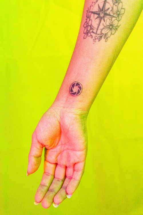 Free Close-up of a woman's forearm with tattoos against a bright yellow background. Stock Photo