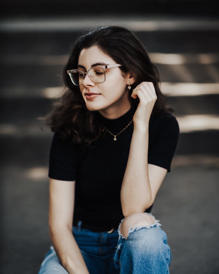 Young Woman In Eyeglasses Sitting Outside 