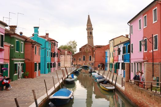 Colorful houses line a canal in Burano, Venice, showcasing vibrant architecture and charming boats.