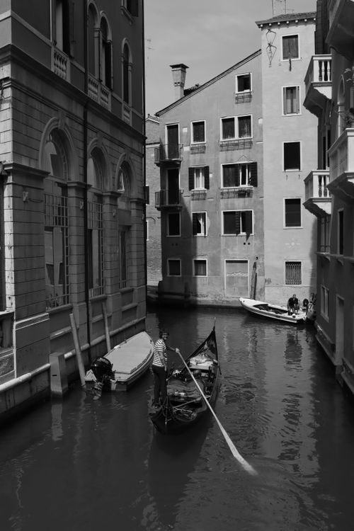 Free Monochrome image of a gondola navigating a canal in Venice, Italy, showcasing classic architecture. Stock Photo