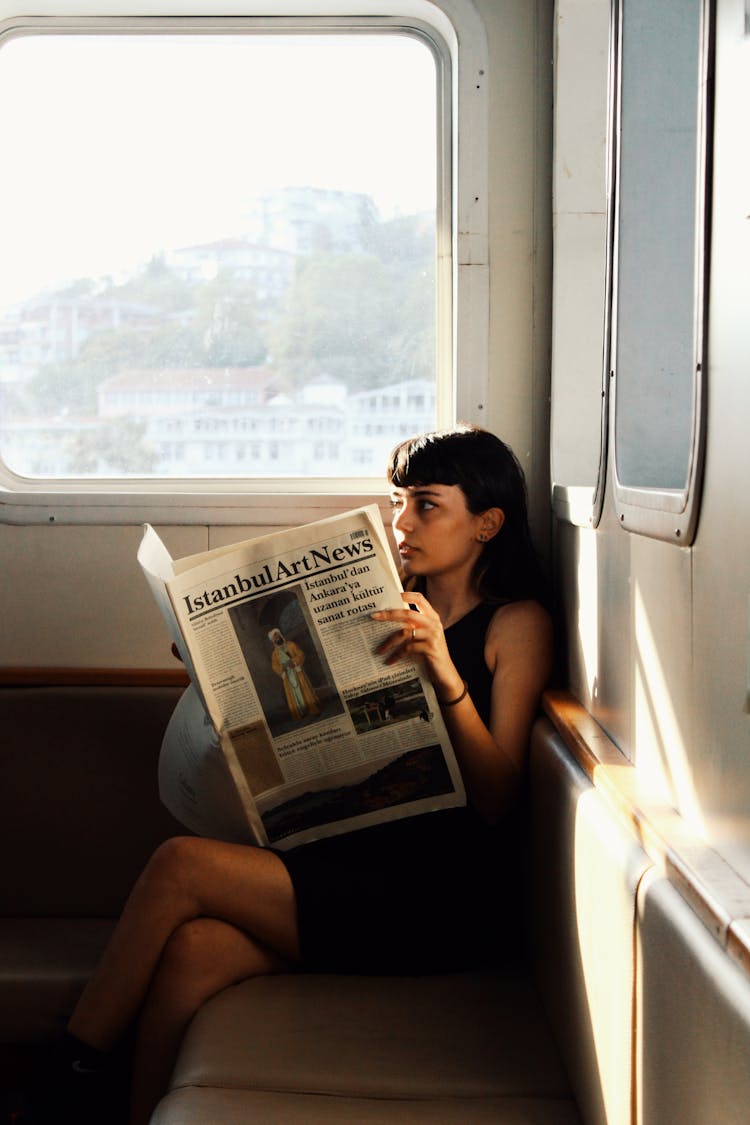 Brunette Woman In Dress Reading Newspaper On Ferry