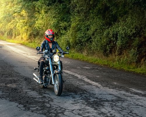 Free A woman on a motorcycle riding through a scenic road in Pachuca, Mexico, wearing a red helmet. Stock Photo