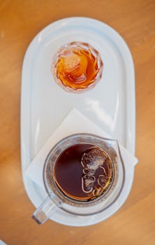 Top view of an iced coffee and juice served on a white tray, perfect for refreshment.