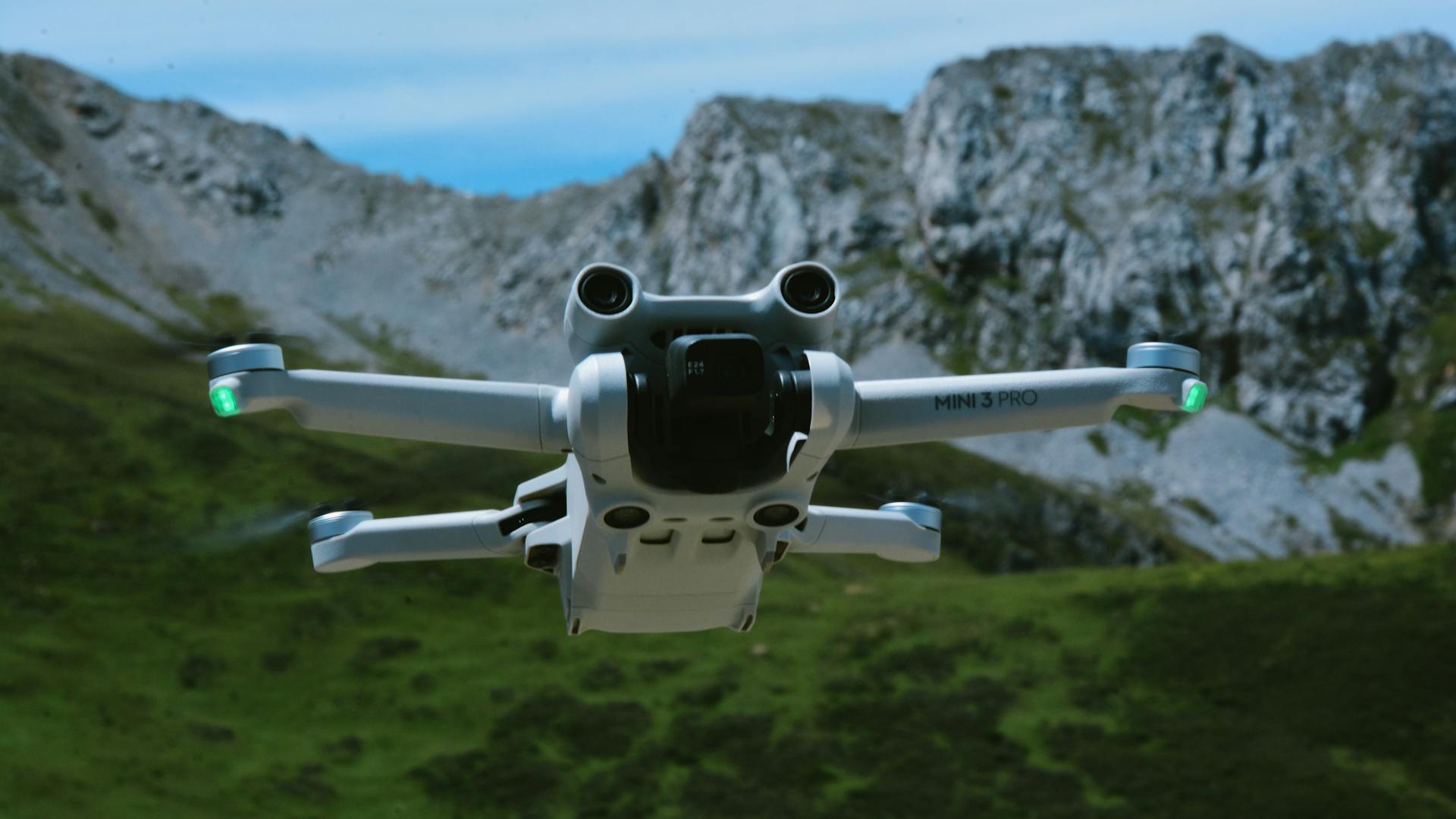 A DJI Mini 3 Pro drone flying over a scenic mountain range with clear skies.