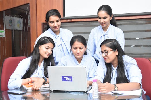 A group of young South Asian women working together on a laptop in a Jaipur office.