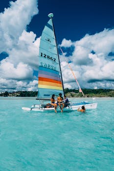 一艘色彩缤纷的帆船旁，人们在清澈碧绿的海水中享受着阳光明媚的一天
